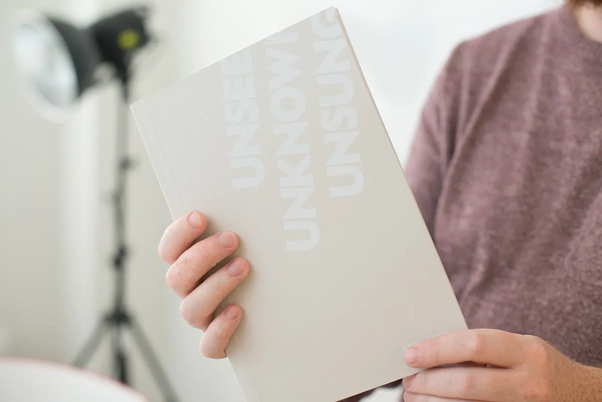 Person holding unseen unknown unsung beige book