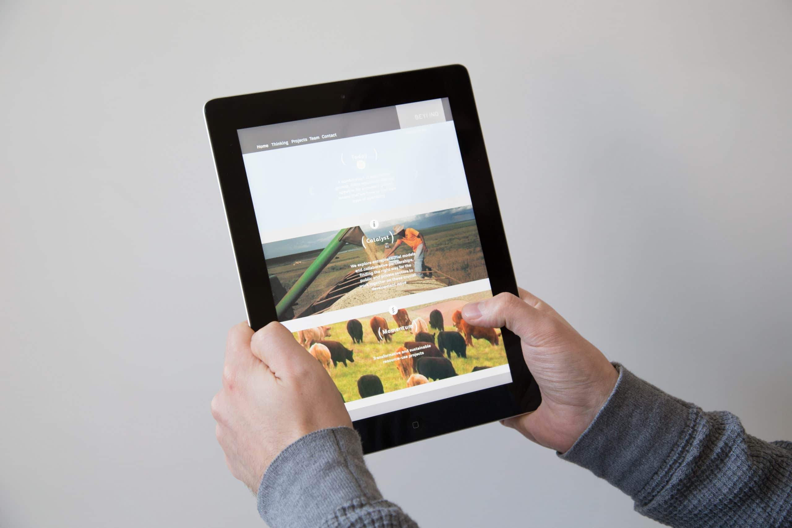 Man with grey sleeves holding iPad with beyond website