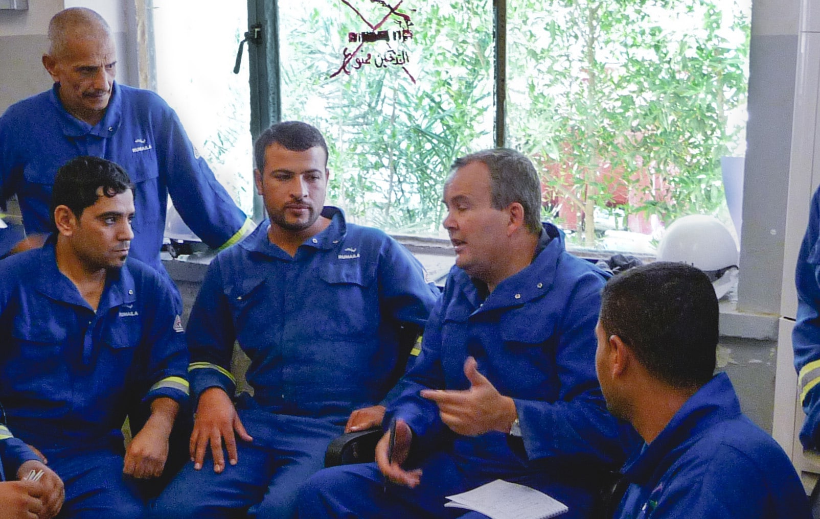 Group of men talking in blue jumpsuits